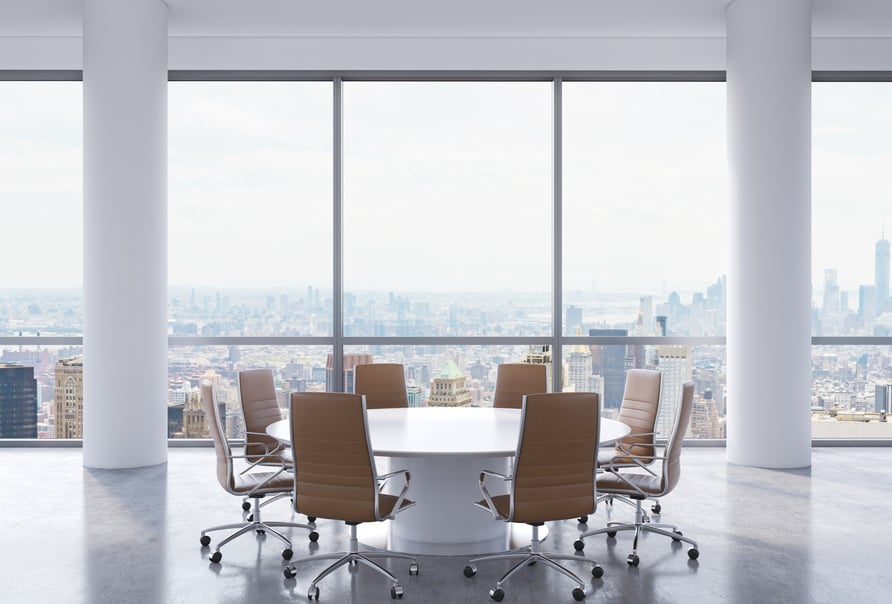 An empty white board table with eight chairs in an office skyscraper overlooking a city